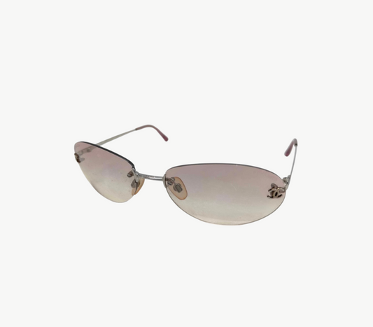 Chanel Rimless sunglasses with a silver-tone metal frame and gradient pink-tinted lenses, shown on a plain off-white background.
